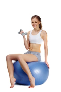 Portrait of a young girl sitting on gymnastic ball with dumbbells
