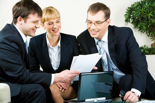 Three people sitting on the sofa and reading the document