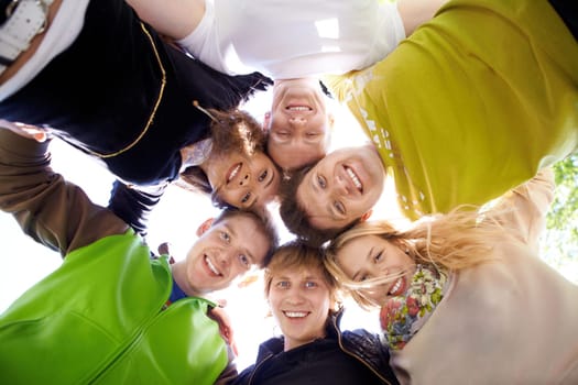 Circle of happy friends looking at camera with smiles
