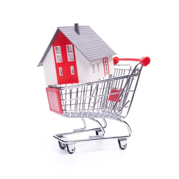 Buy new house concept - model of the house in shopping cart on white background.