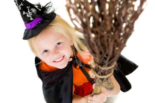 Above angle of girl in halloween costume and broom smilling at camera