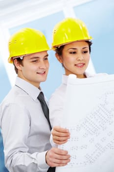 Portrait of two architects in helmets looking document at meeting
