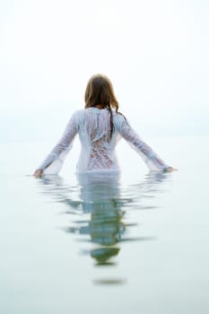 Rear view of beautiful female bathing in blue water