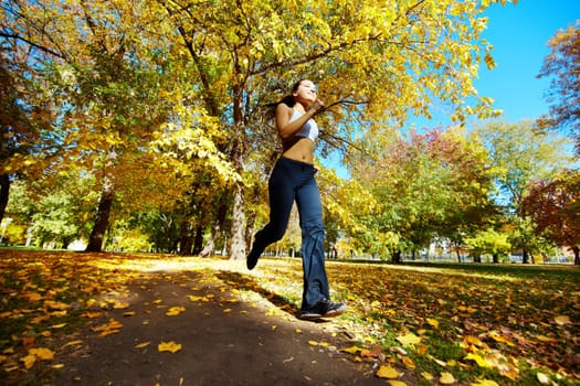 A young girl running in autumn park