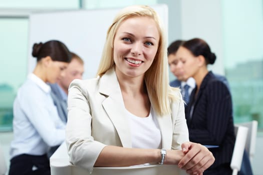 Portrait of business leader looking at camera and smiling with her colleagues in the background