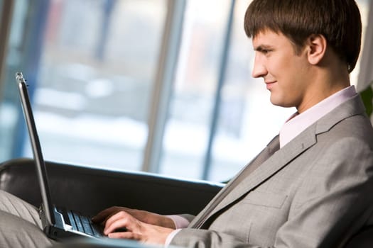 Photo of successful manager typing on laptop and looking at its screen
