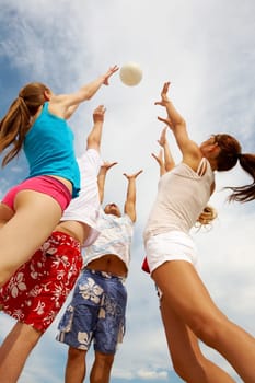 Photo of teenage friends playing with ball on background of cloudy sky