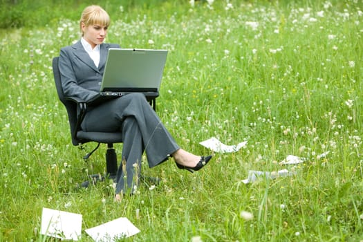 Photo of pretty specialist sitting in armchair on green grass with laptop and working