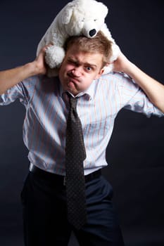 Portrait of young man carrying soft teddy bear showing difficulty