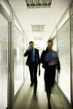 Portrait of business people walking down long corridor in office building