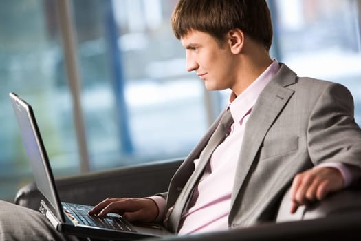 Photo of smart businessman working on laptop in office