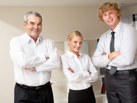 Group of positive three colleagues standing and folding their hands