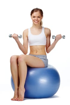 Portrait of a young girl sitting on gymnastic ball, looking at camera and smiling