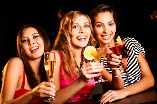 Portrait of happy girlfriends holding martini glasses with cocktails