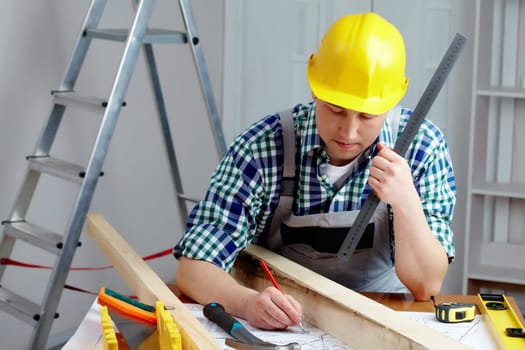 A young repairmen sitting at table and working with a plan