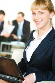 Portrait of cheerful specialist in suit holding the laptop