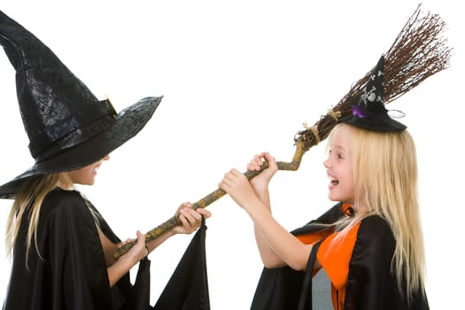 Portrait of girl twins in black hats and black clothing sharing broom