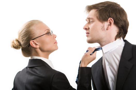 Image of business woman holding by mans tie and both looking at each other