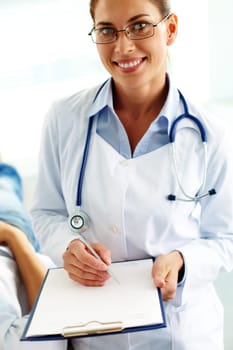 Portrait of confident female doctor with stethoscope and clipboard looking at camera in hospital