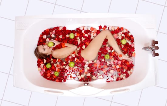 Portrait of attractive woman lying in the bathtub and eating apple