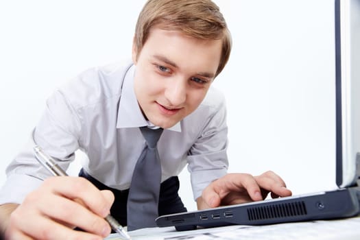 Portrait of confident businessman making notes with laptop near by