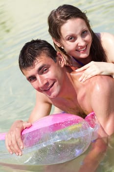 Portrait of happy couple in water looking at camera with smiles