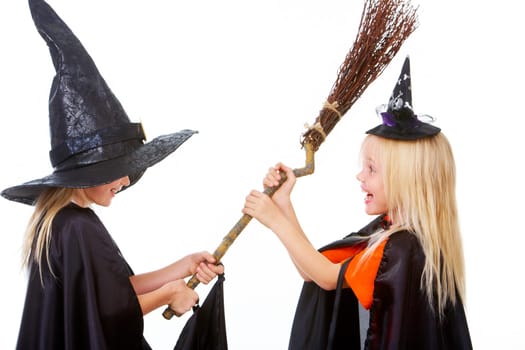 Portrait of girl twins in black hats and black clothing sharing broom