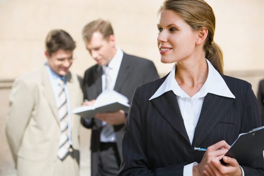 Successful young woman is writing a text on the background of two businesspeople
