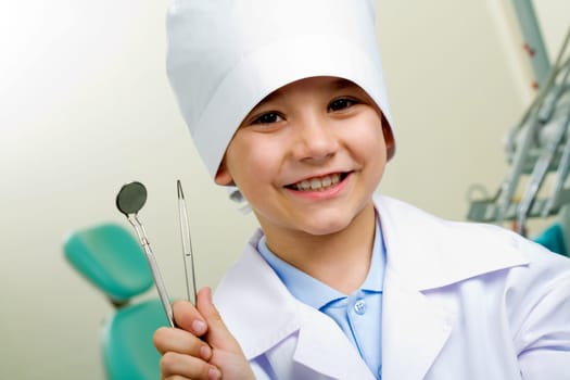 Portrait of happy boy in medical uniform holding dentistry tools in hand