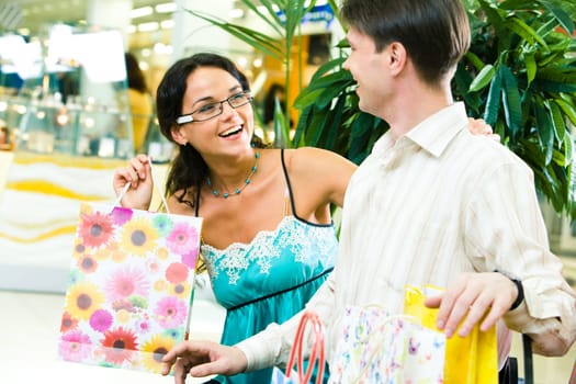 Image of beautiful girl looking happily at young man and laughing in the store