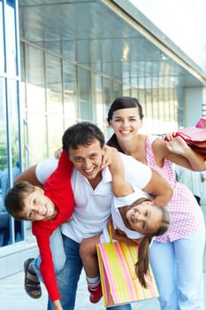 Portrait of happy family of four with shopping bags having fun