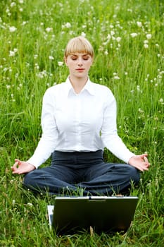 Portrait of businesswoman sitting on the grass and meditating