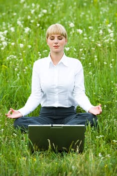 Portrait of businesswoman sitting on the grass and meditating