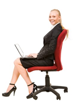 Profile of serious businesswoman sitting on arm-chair and smiling at camera while typing