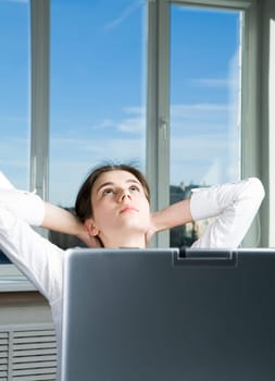 Portrait of thoughtful business lady with hands behind her head looking upwards in workshop