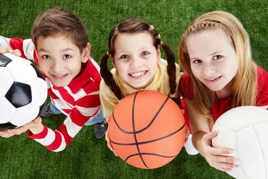 Image of happy friends on the grass with balls looking at camera