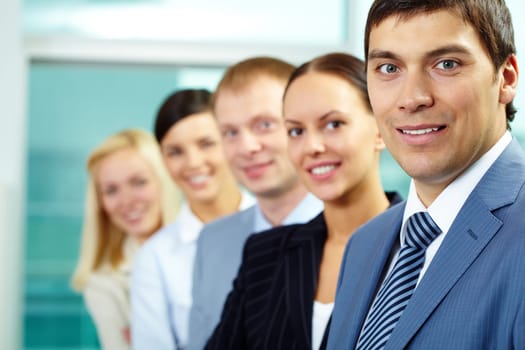 Portrait of friendly leader looking at camera with four employees behind