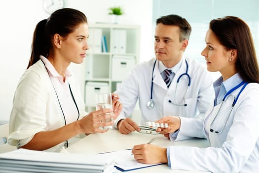 Portrait of confident practitioners prescribing tablets to patient in hospital