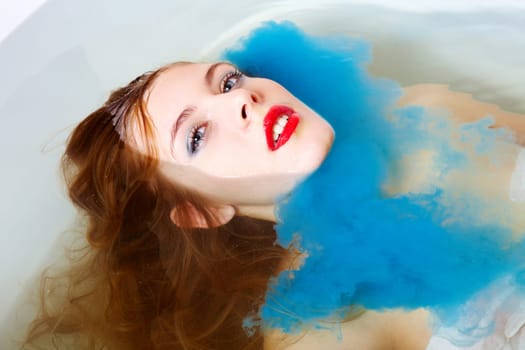 Close-up of woman taking bath with blue paint