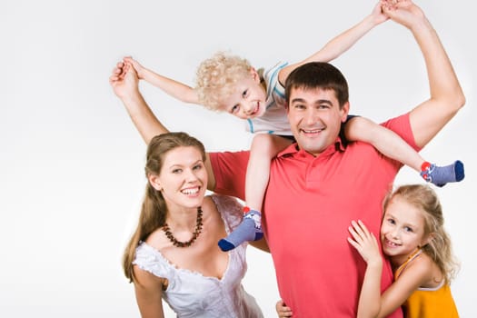Image of woman and girl embracing man holding son on his neck