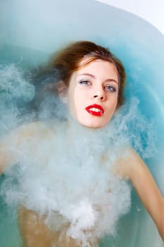 Close-up of pretty woman with make-up lying in bath