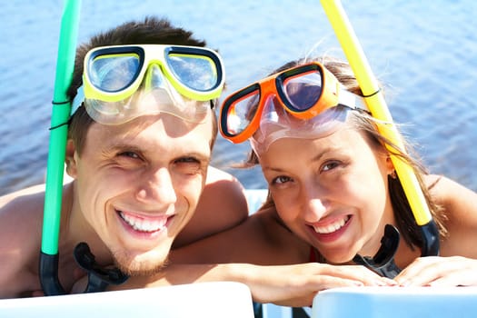 Portrait of cheerful couple in aqualungs looking at camera with smiles