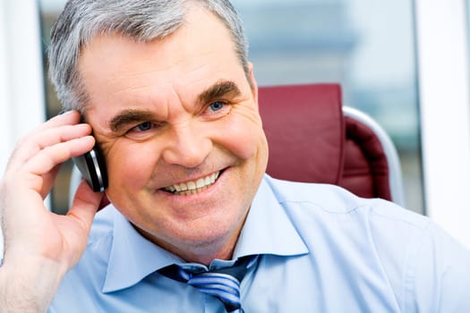 Portrait of a smiling senior businessman speaking on the cellular phone