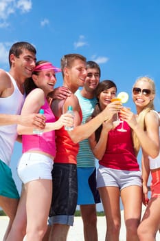 Portrait of happy young friends holding cocktails during beach party