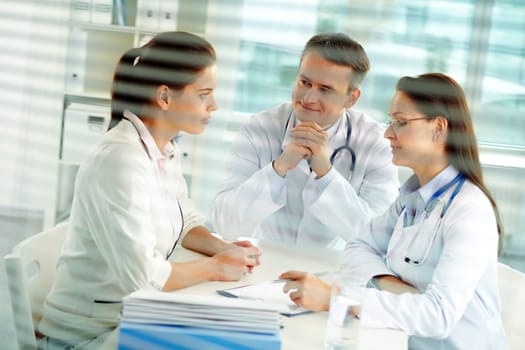 Portrait of confident practitioners consulting patient in hospital