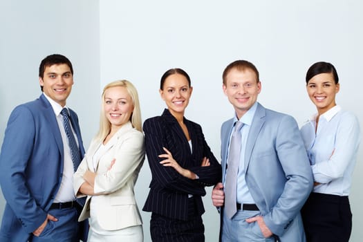 A business team of five looking at camera and smiling
