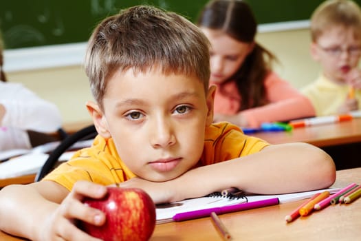 Close-up of schoolboy putting his head on arm and looking at camera