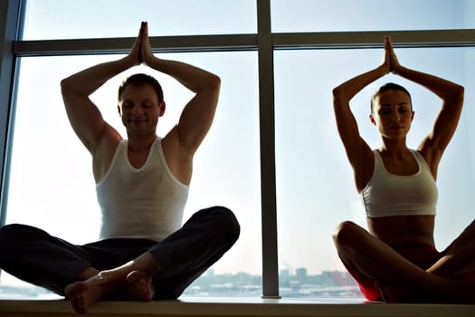 Photo of meditating people sitting with their arms raised and kept in touch