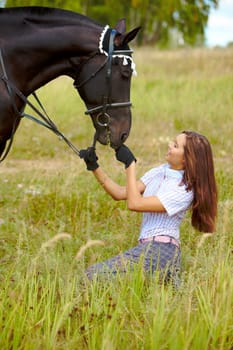 Portrait of smiling female feeding purebred horse with grass outdoors