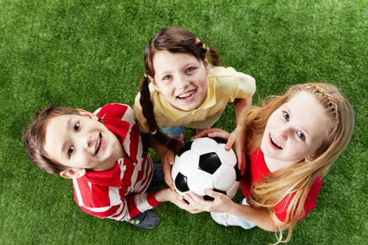 Image of happy friends on the grass with ball looking at camera